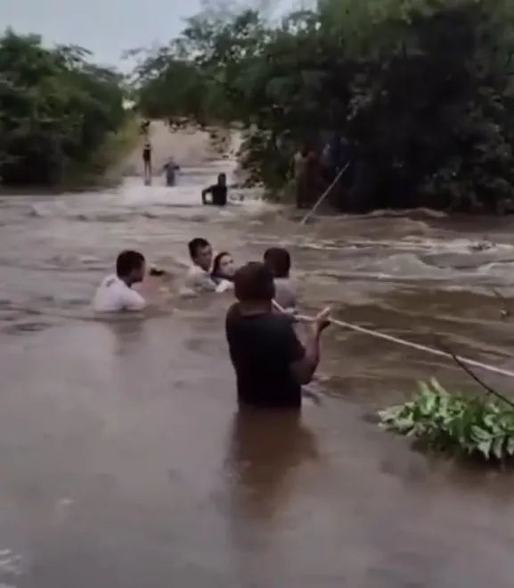 Moradores se seguram em corda em meio a enchente. Foto: Reprodução