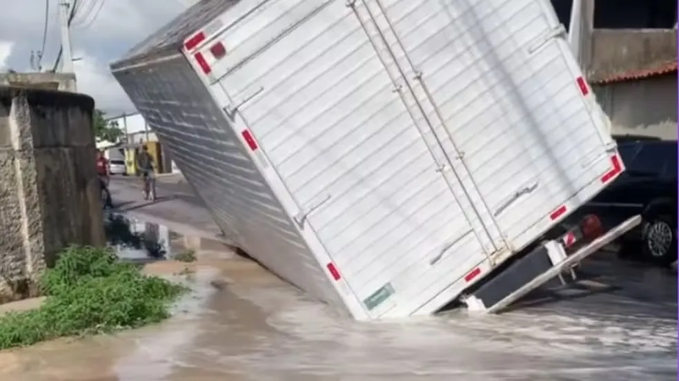 Caminhão fica preso em buraco aberto na pista por vazamento de água